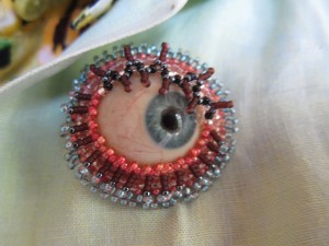 Andrea Hartman turns prosthesis glass eye into artful brooch.